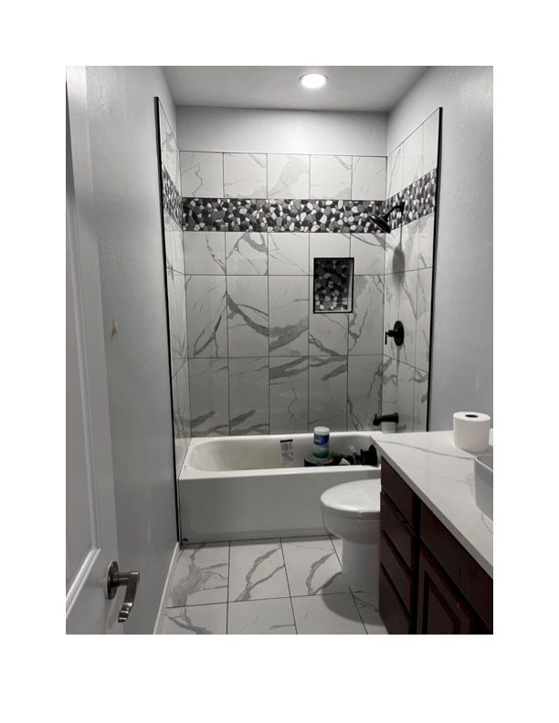 A bathroom with a tub , toilet , sink and shower.