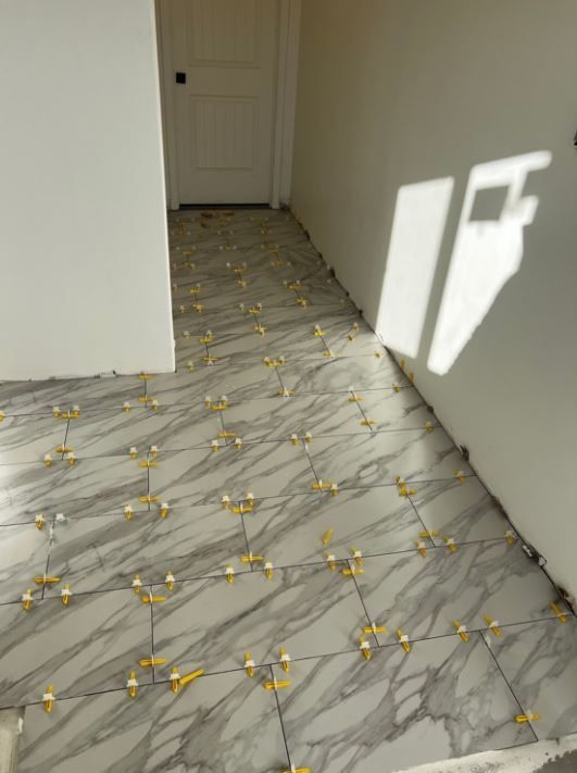 A hallway with tiles on the floor and a door in the background.