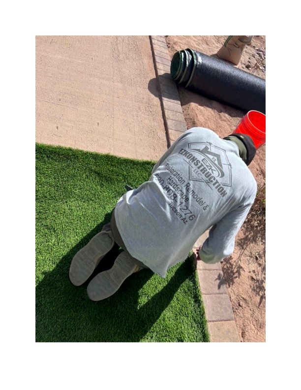 A man wearing a shirt that says ' synthetic grass ' on it. Turf is installed
