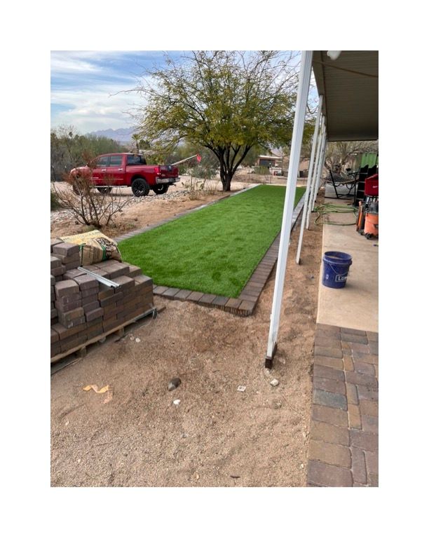 A red truck is parked in the backyard of a house. Turf is installed