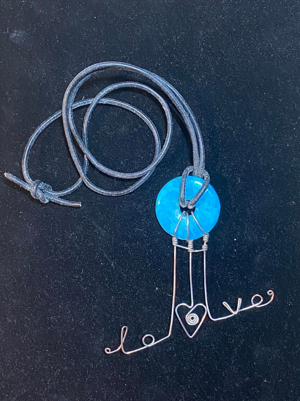 Turquoise donut, wire wrapped with the word love on leather.