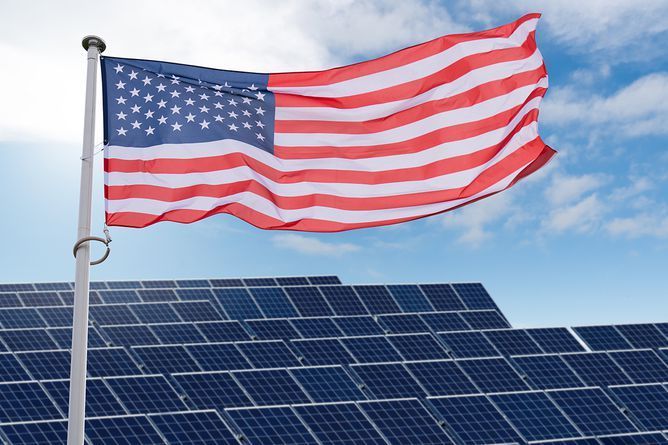 An american flag is waving in front of a row of solar panels