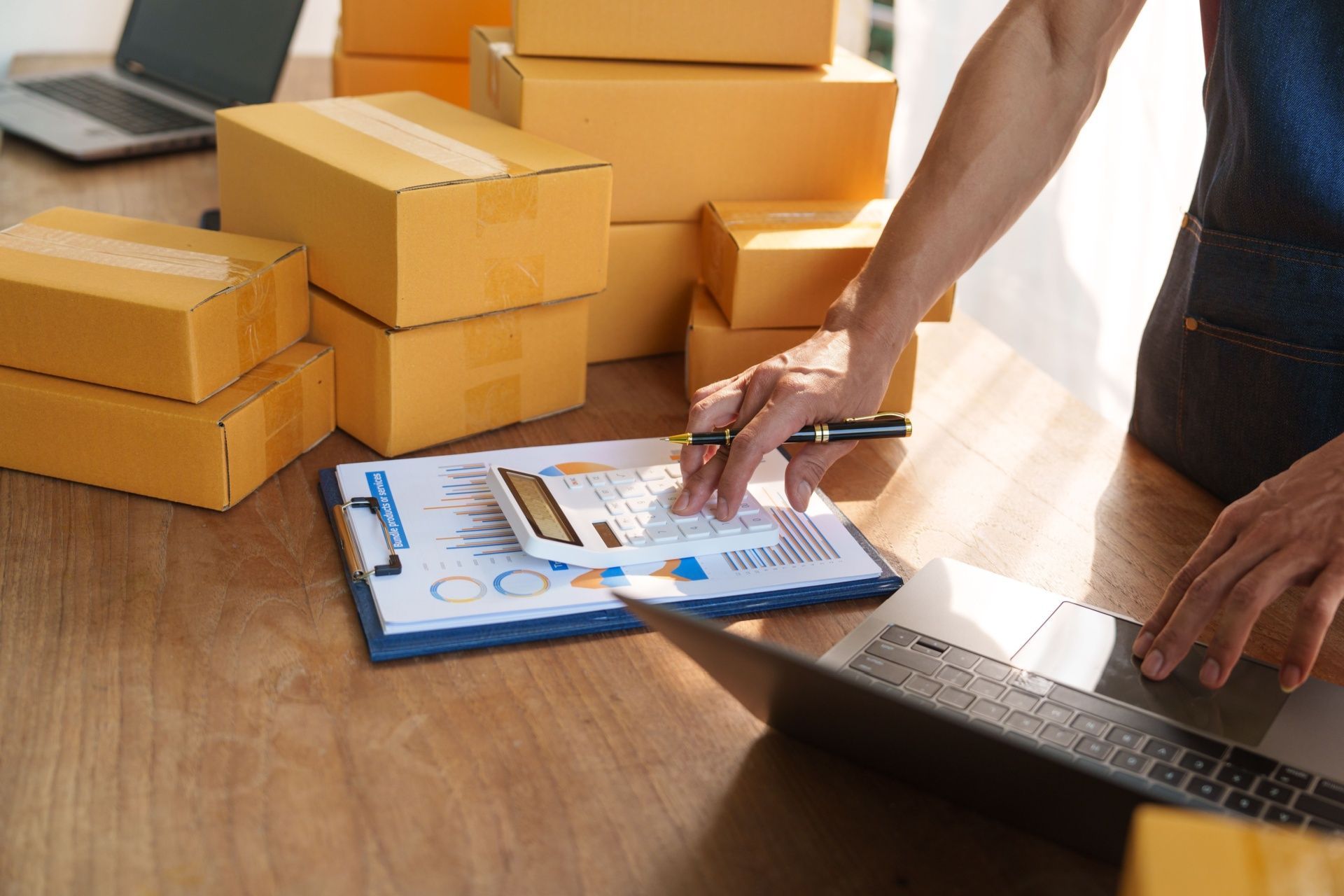 A man is sitting at a table with boxes and a laptop.