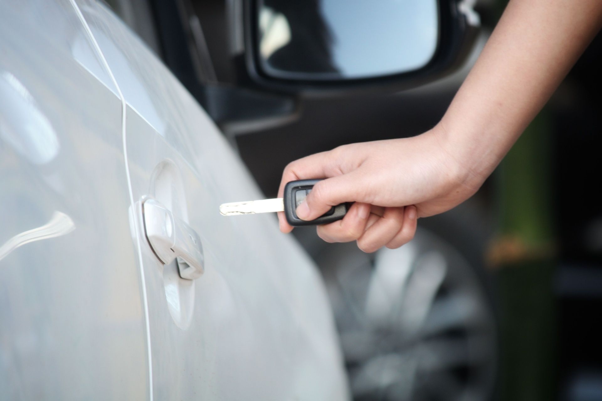 A person is opening a car door with a key.