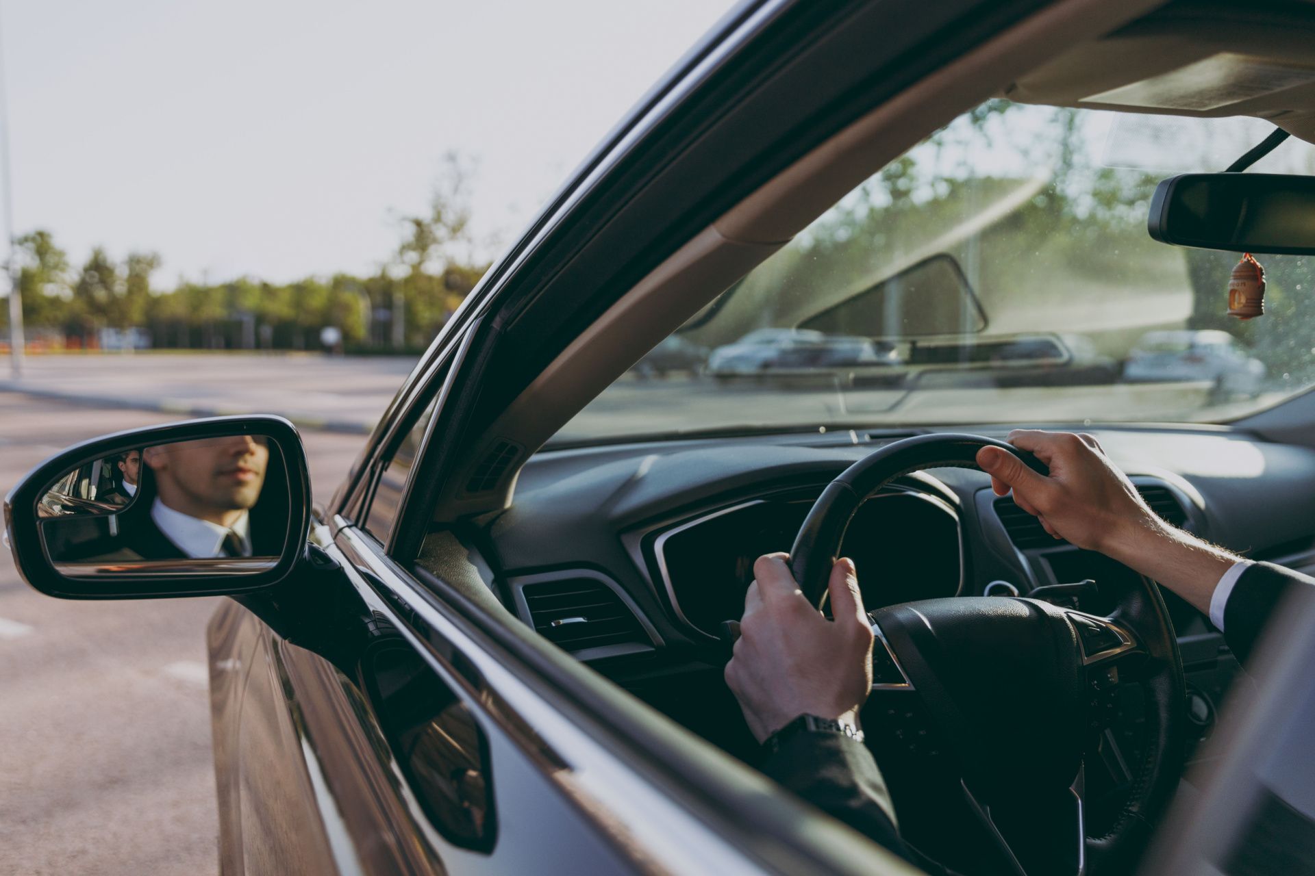 A man in a suit and tie is driving a car.