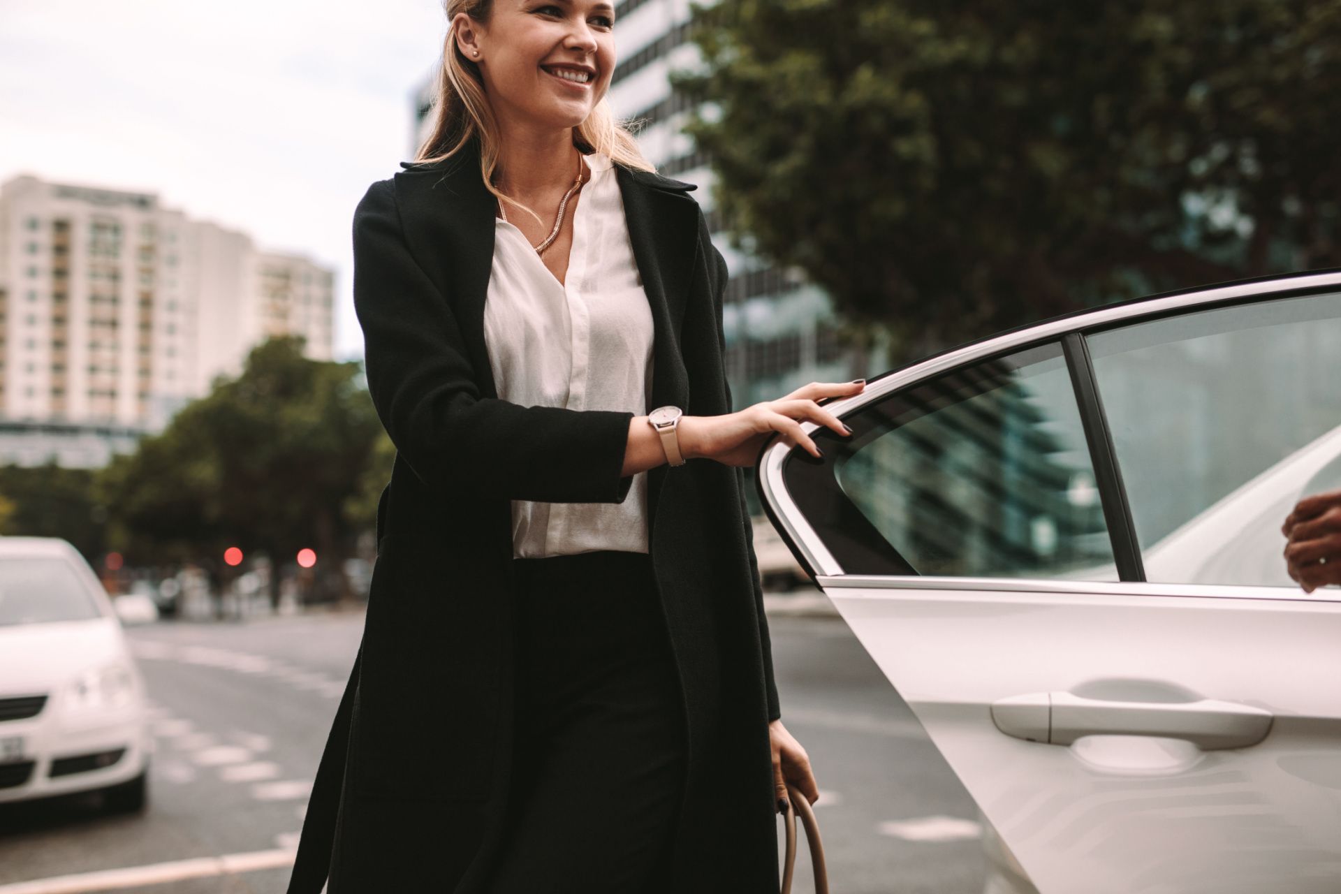 A woman is getting out of a car on a city street.