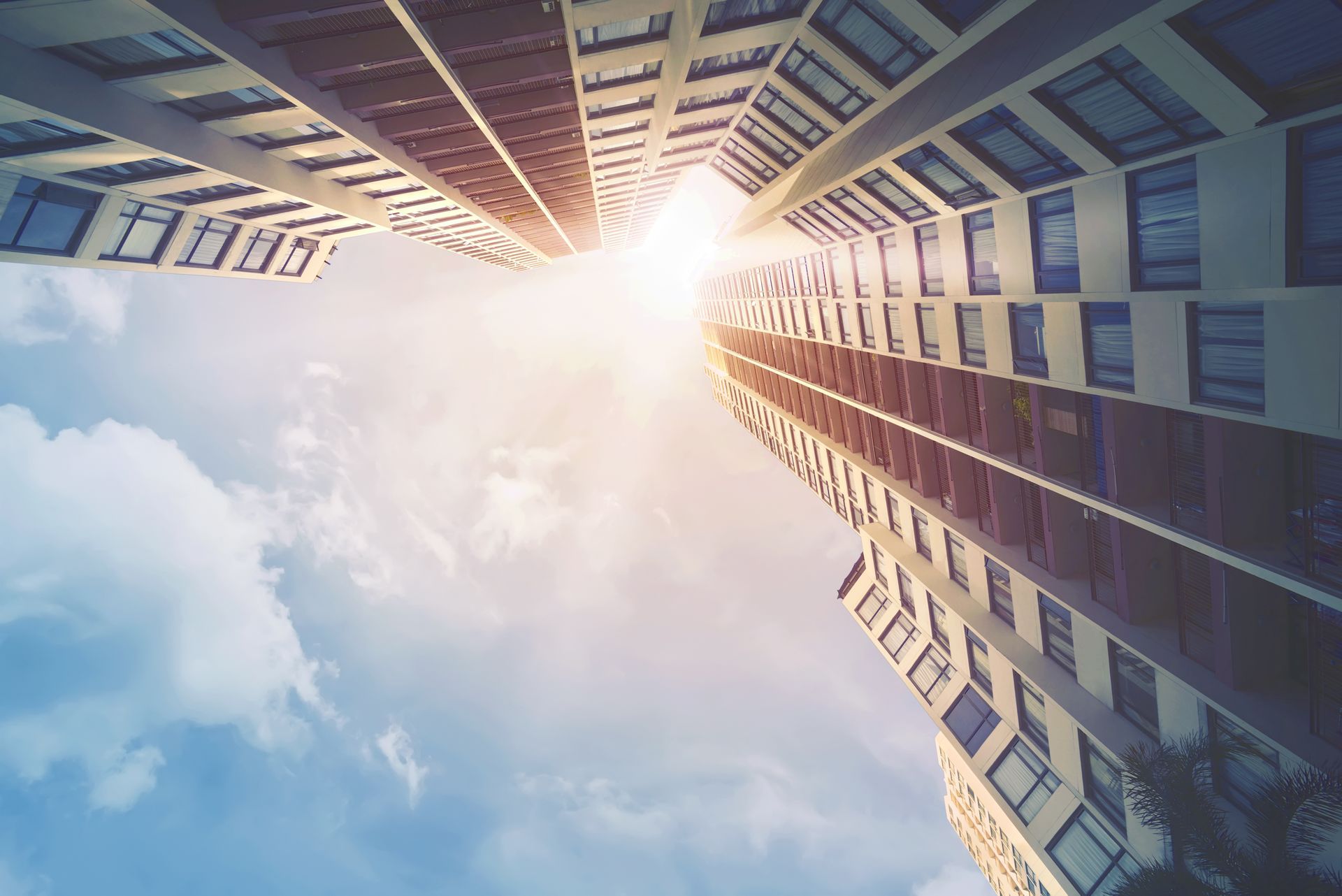 Looking up at a tall building with the sun shining through the windows.