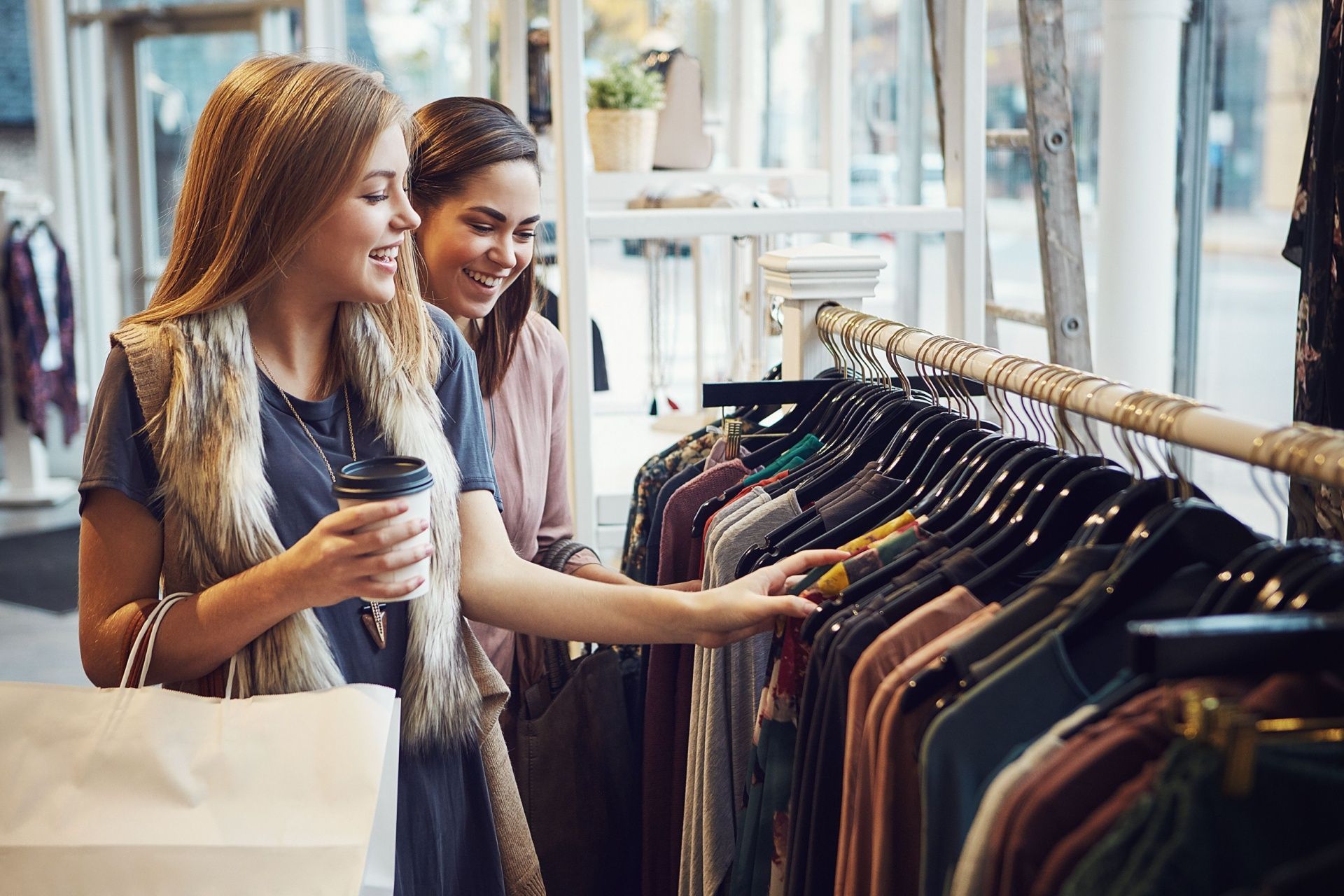 Two women are shopping for clothes in a clothing store.