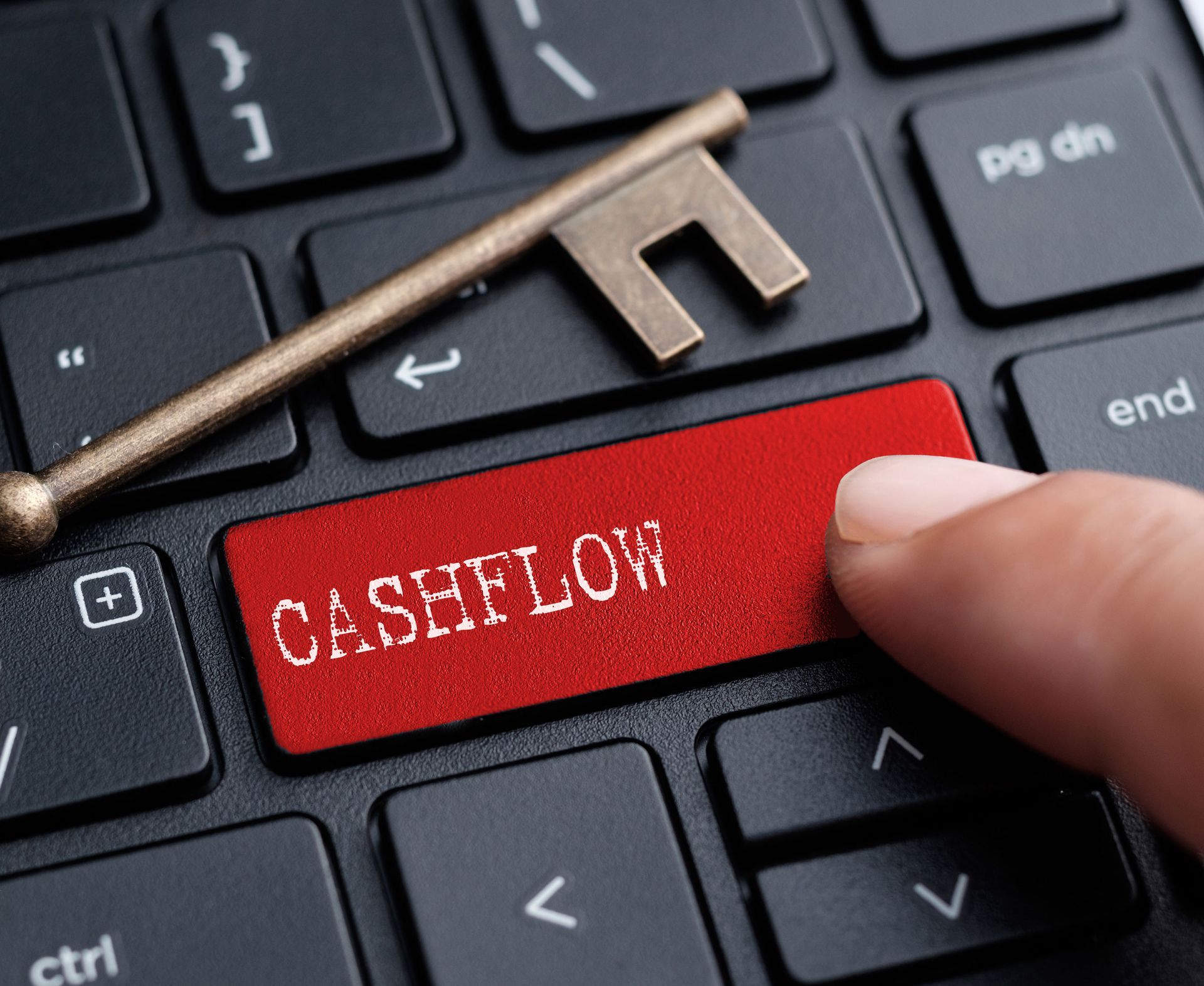 A person is pressing a red cashflow button on a keyboard