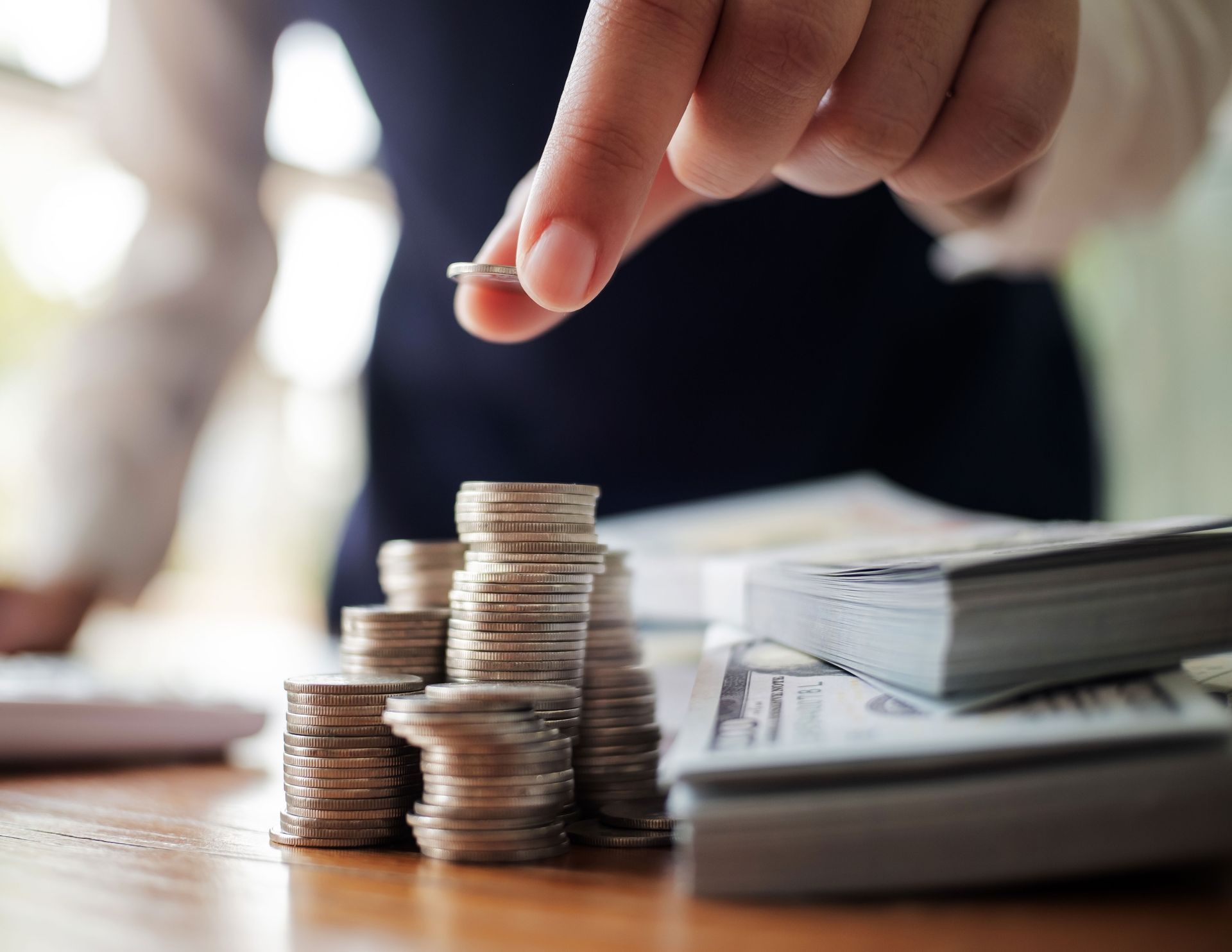 A person is stacking coins on top of each other on a table.