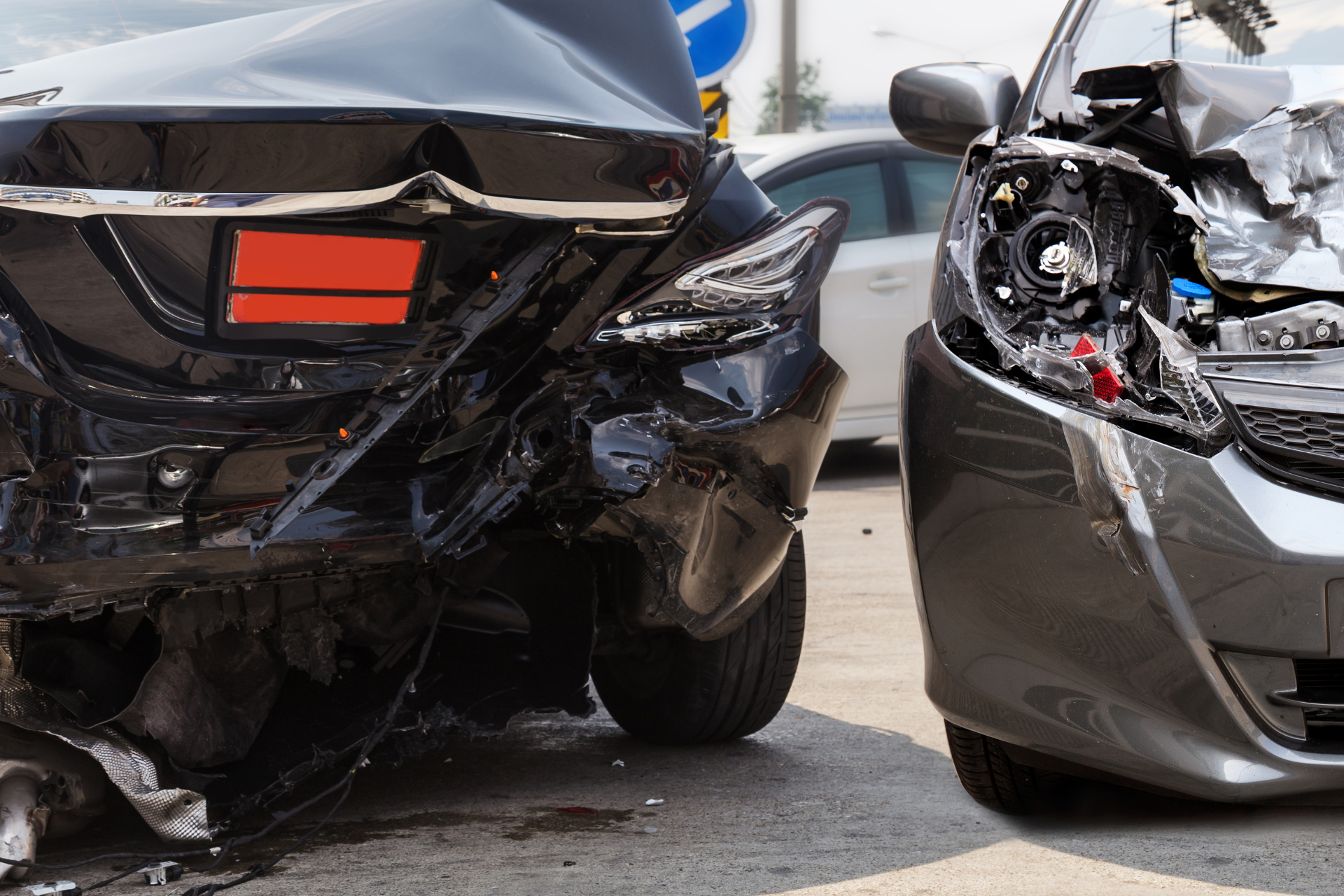 Two cars are damaged in a car accident on a city street.