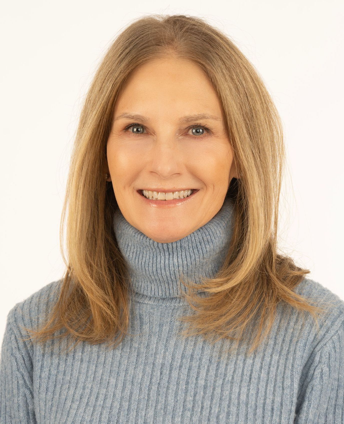 A woman in a blue sweater is smiling for the camera.