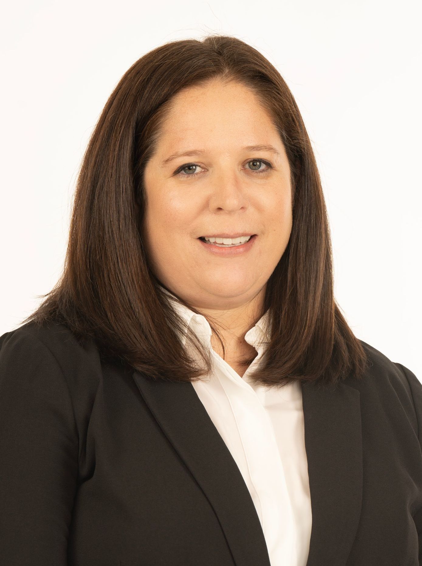 A woman in a black jacket and white shirt is smiling for the camera.