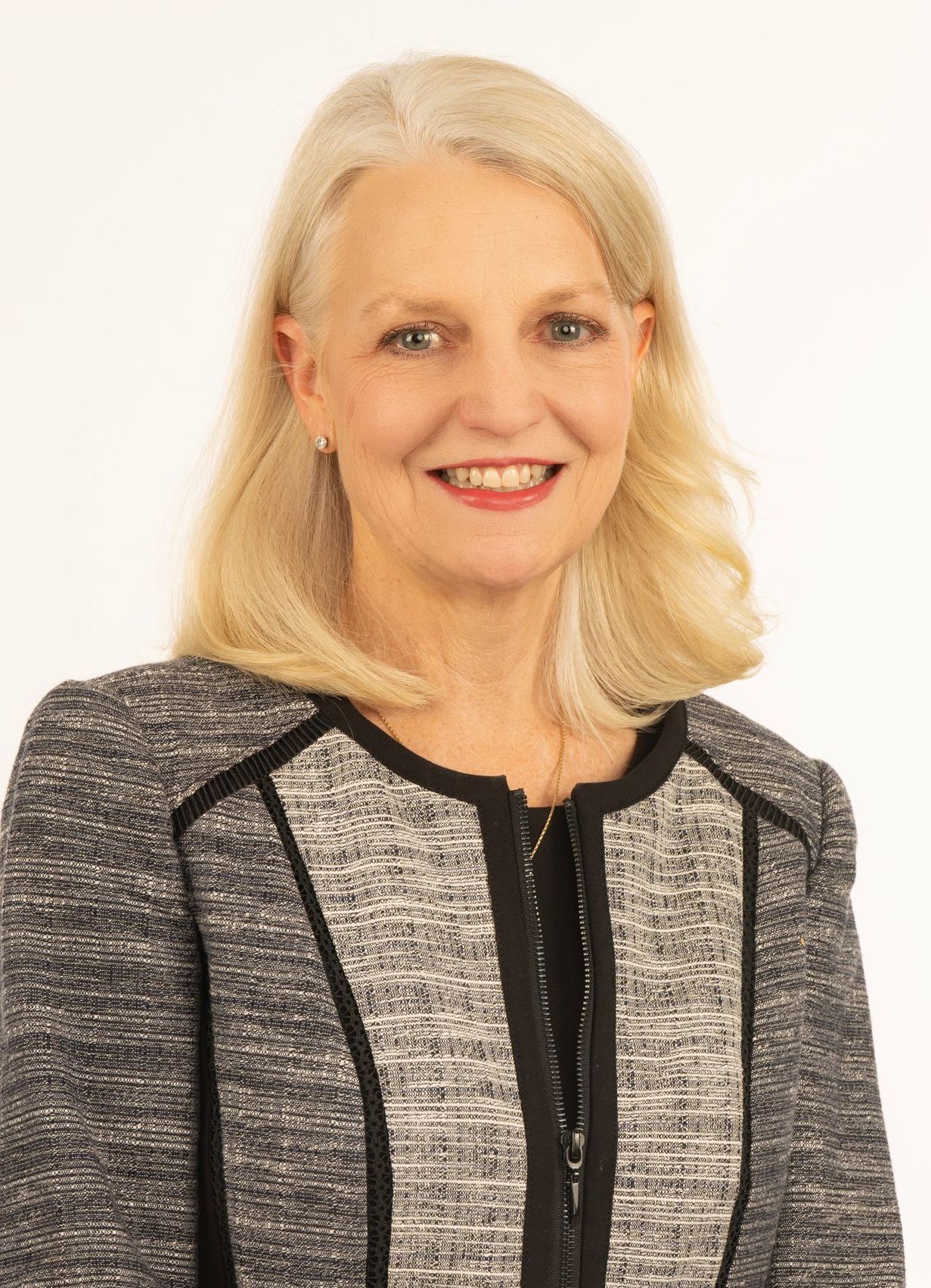 A woman in a gray and black jacket is smiling for the camera.