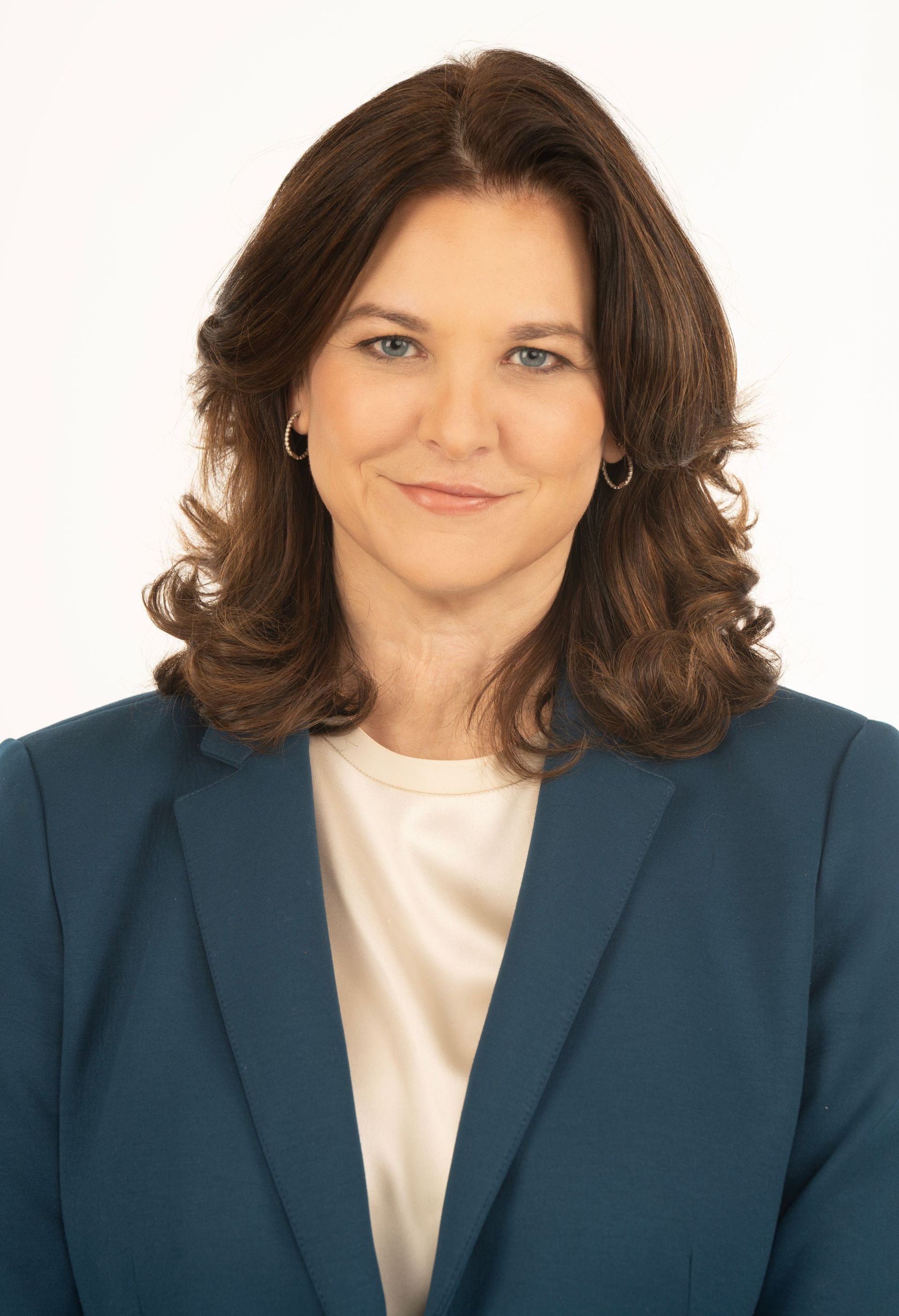 A woman in a blue jacket and white shirt is smiling for the camera.