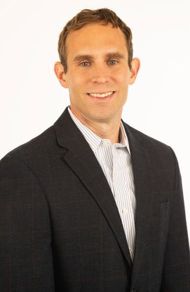 Attorney Trent Shuping in a suit and tie is smiling for the camera.
