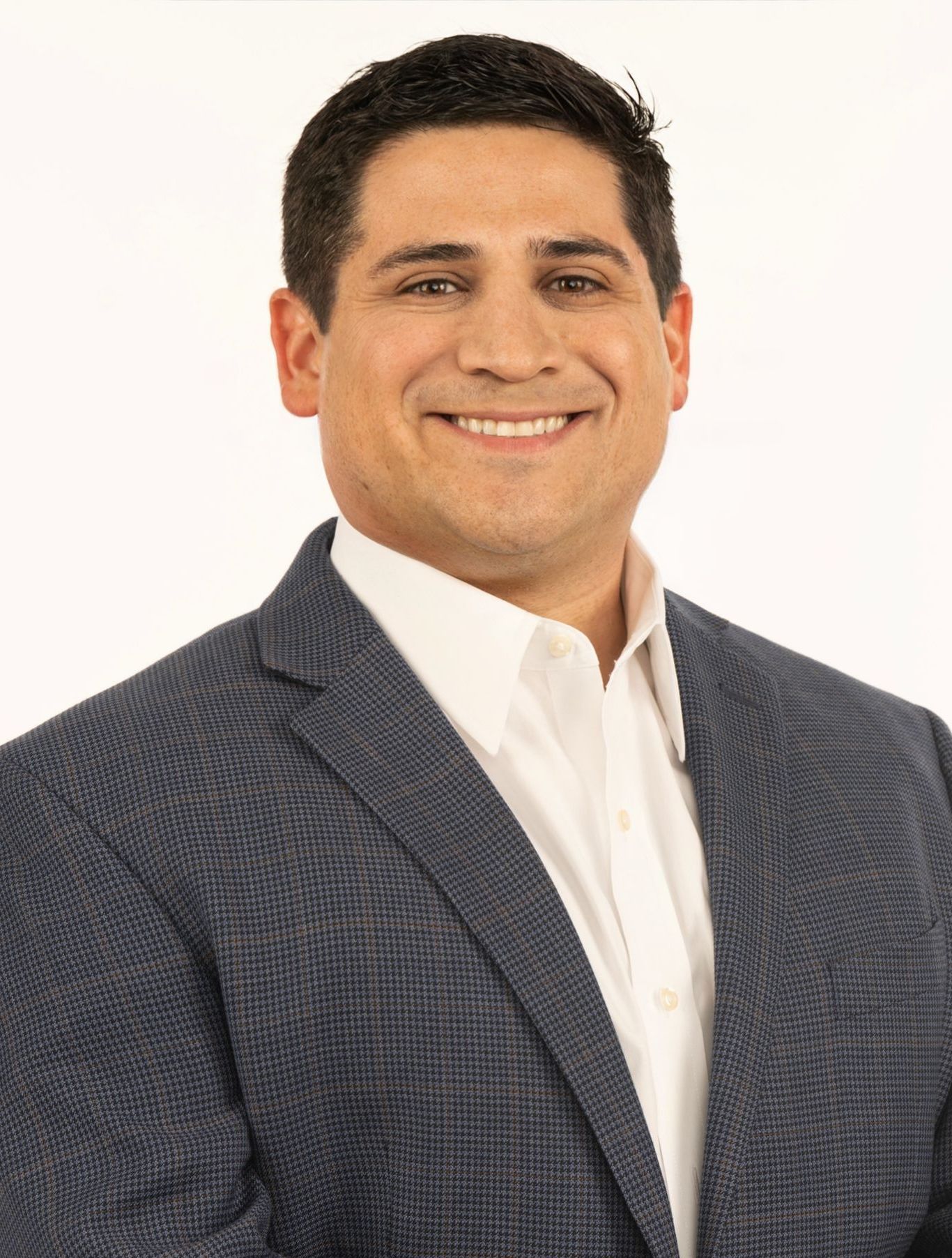 A man in a suit and white shirt is smiling for the camera.
