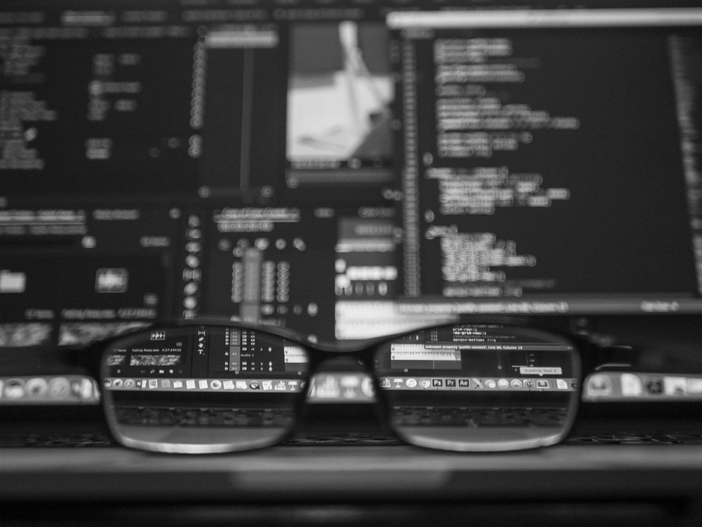 Blonde woman smiles at camera, wearing black dress, in front of a bookshelf.