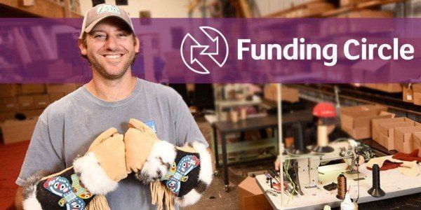 A man is holding a pair of gloves in front of a sign that says funding circle