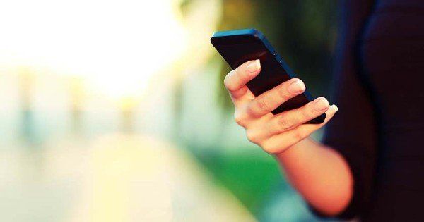 A woman is holding a cell phone in her hand.