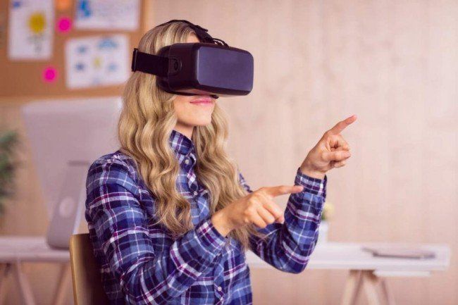 A woman is wearing a virtual reality headset and pointing at something.