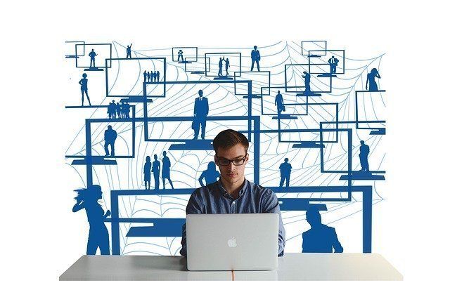 A man is sitting at a desk using a laptop computer.