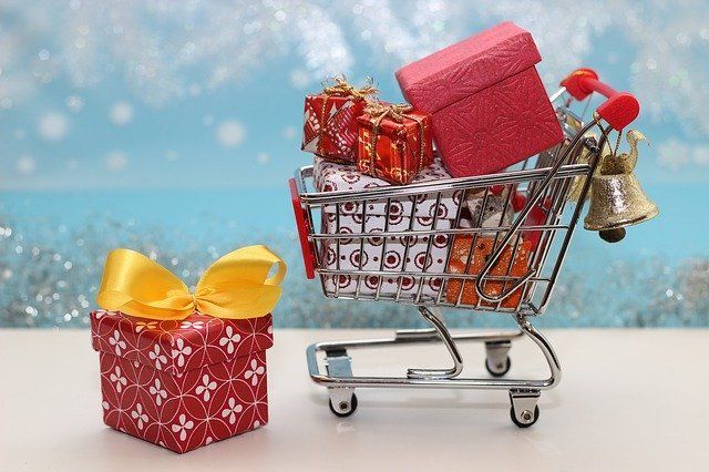 A shopping cart filled with christmas presents and bells.