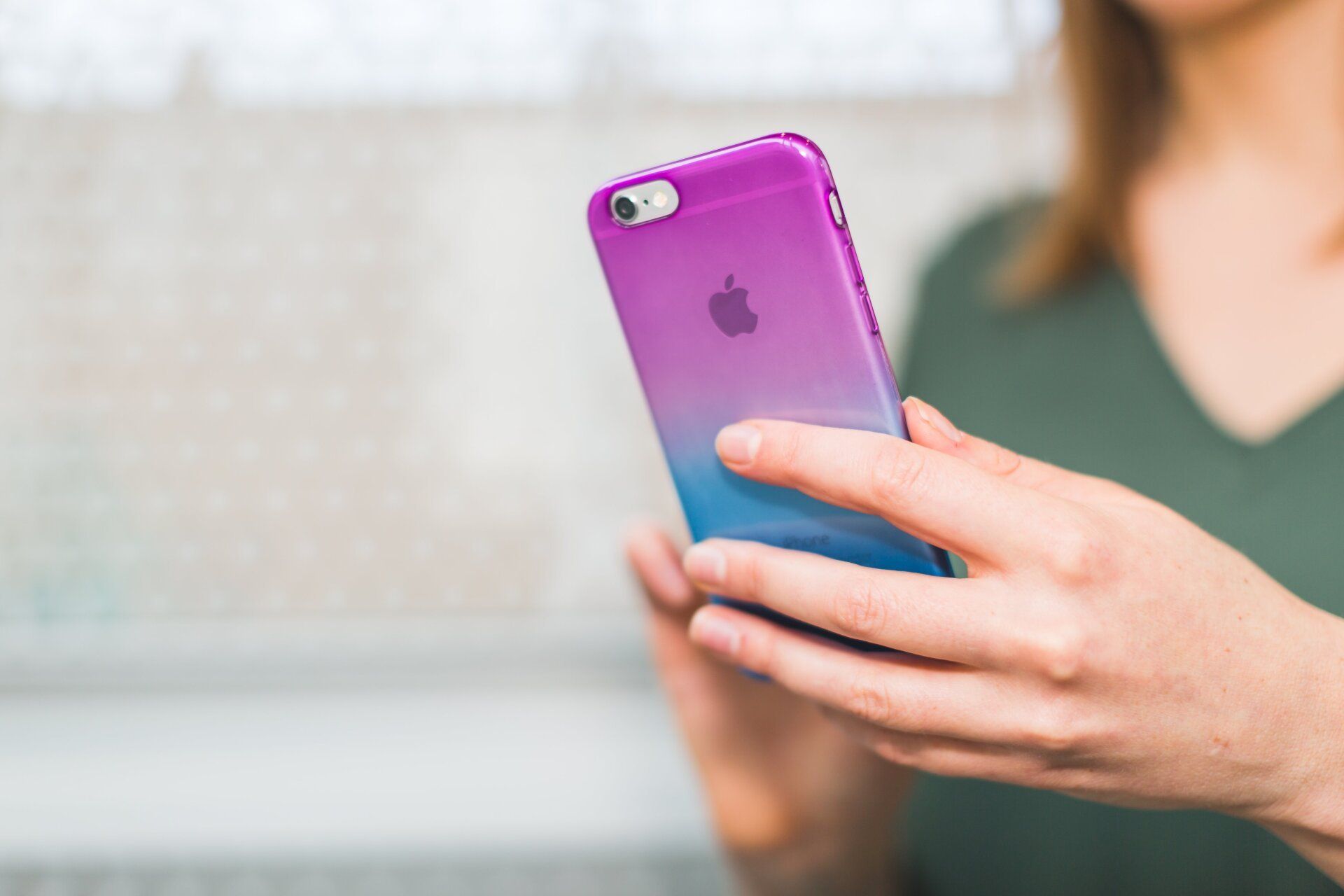 A woman is holding a purple and blue iphone in her hands.