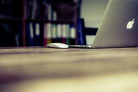 A laptop and a mouse are on a wooden table.