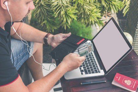 A man is sitting at a table using a laptop computer.