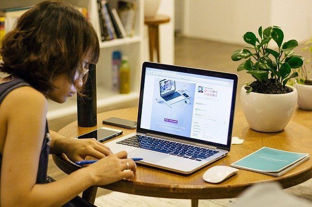 A woman is sitting at a table using a laptop computer.