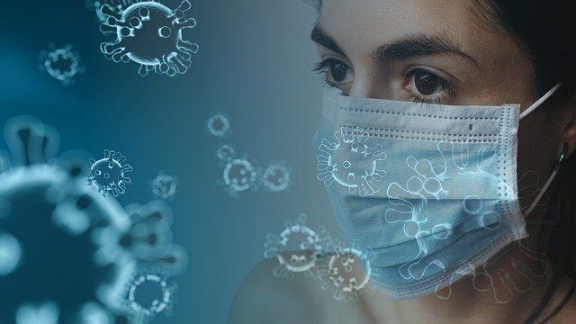 A woman wearing a medical mask is looking at a virus.