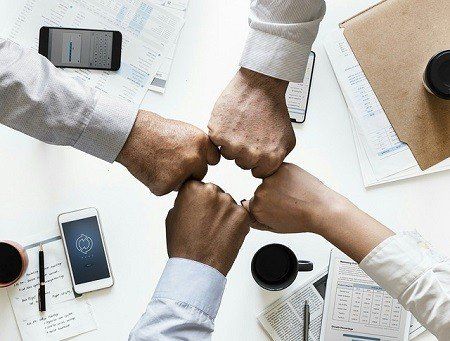 A group of people are putting their fists together in a circle.