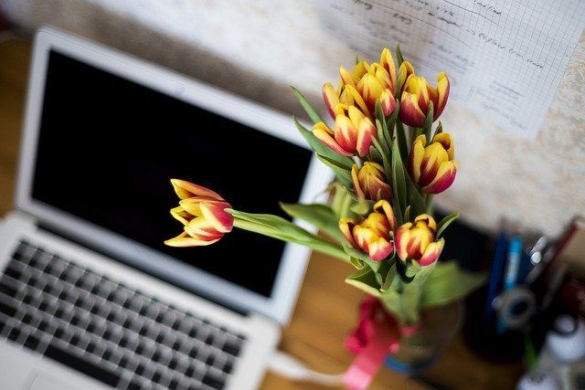 A laptop with a bunch of flowers in front of it