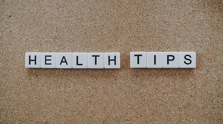 The word health tips is written in white tiles on a cork board.