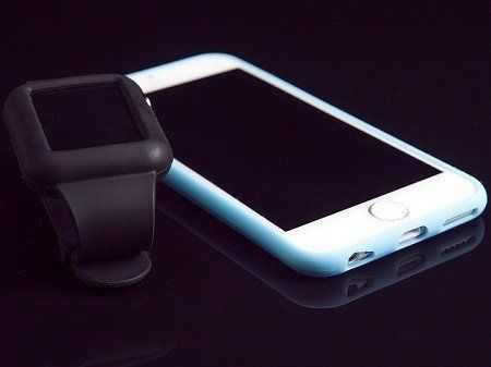 A smart watch sits next to a smart phone