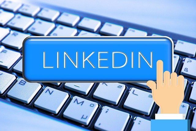 A hand is pressing a blue button that says linkedin