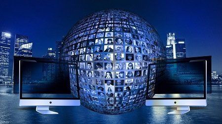 Two computer monitors are sitting in front of a globe made of pictures.