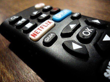 A close up of a netflix remote control on a wooden table