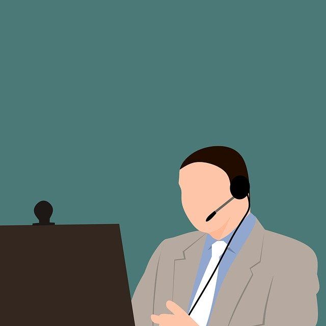 A man in a suit and tie is wearing a headset while sitting in front of a computer.