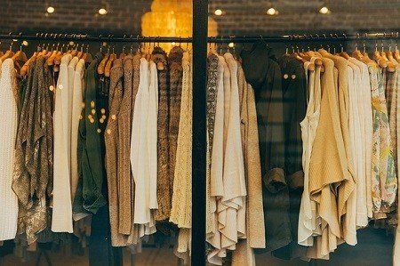 A row of clothes hanging in a store window.