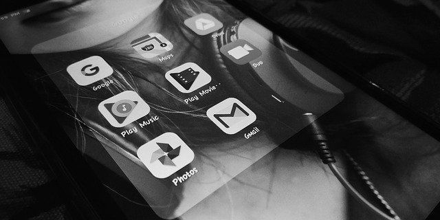 A black and white photo of a cell phone with icons on the screen.