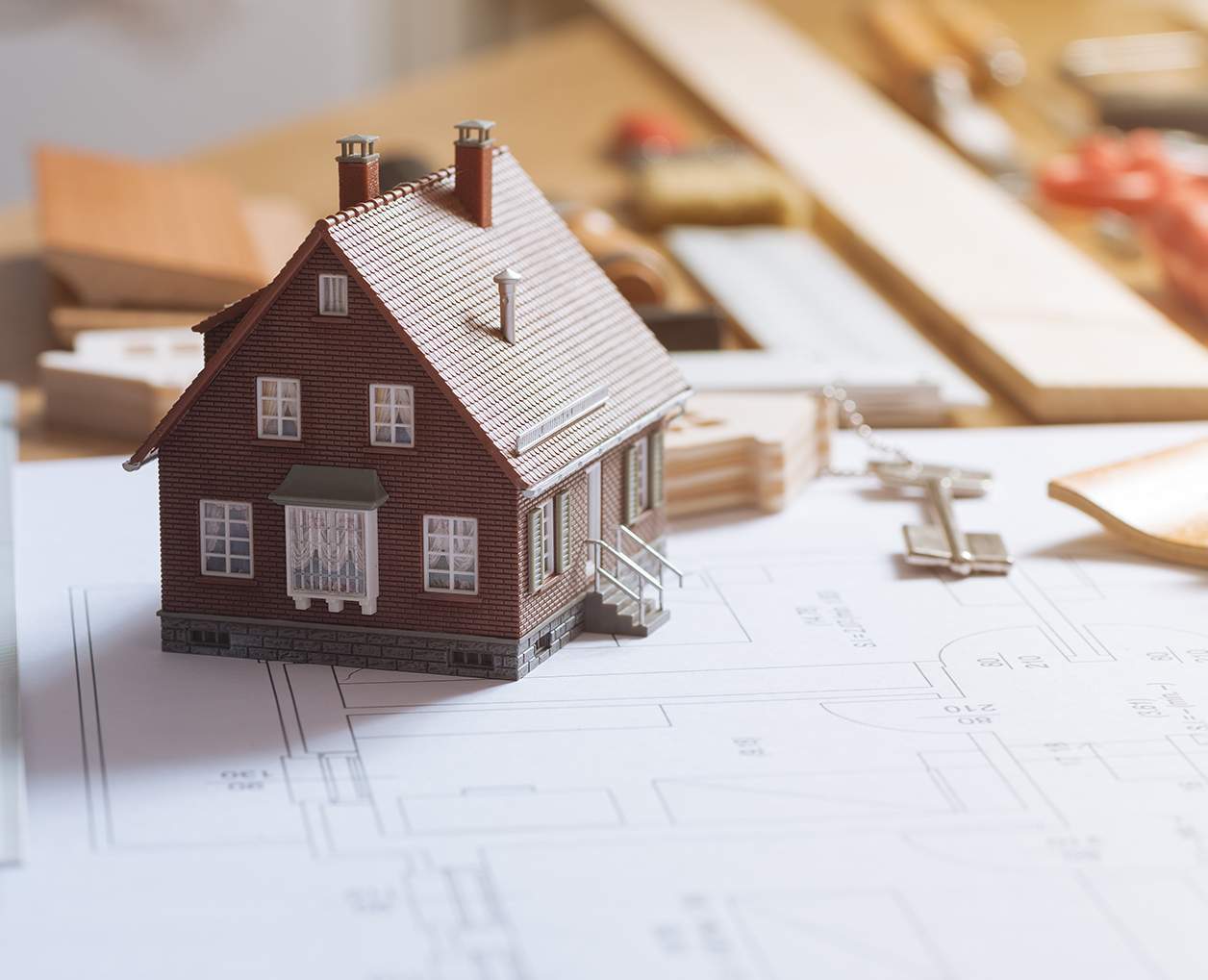 A small model house is sitting on top of a blueprint.