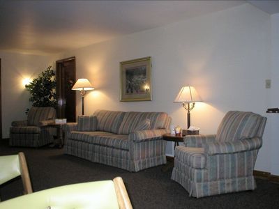 A waiting room with striped sofas, armchairs, lamps, and a framed picture on the wall.