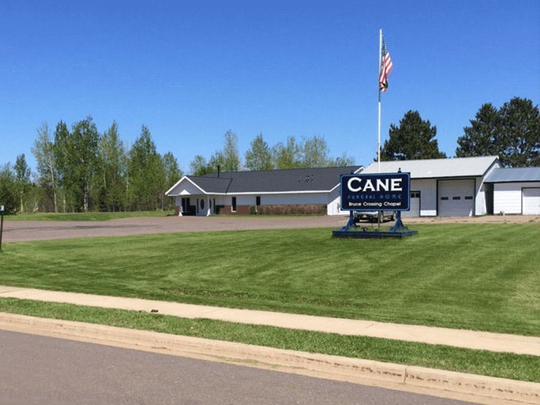 CANE Welcome Center sign in front of a white building with a US flag, on a sunny day.