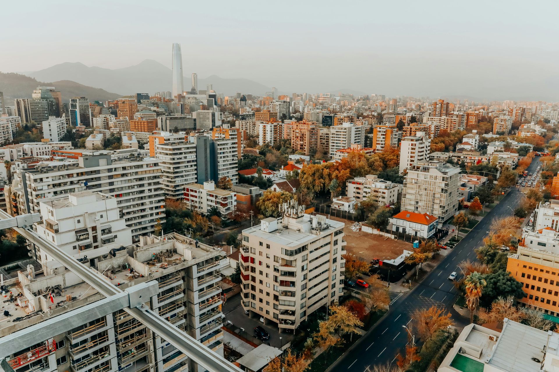 Vista de paisaje urbano con edificios altos, calles y montañas al fondo, bajo un cielo nublado.