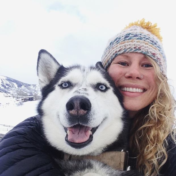 A woman is posing for a picture with her husky dog