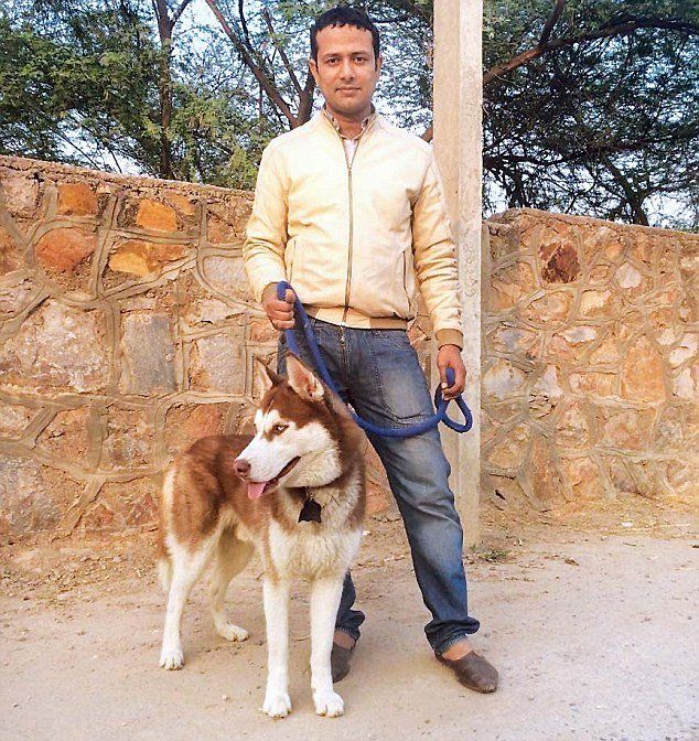 A man standing next to a brown and white dog on a leash
