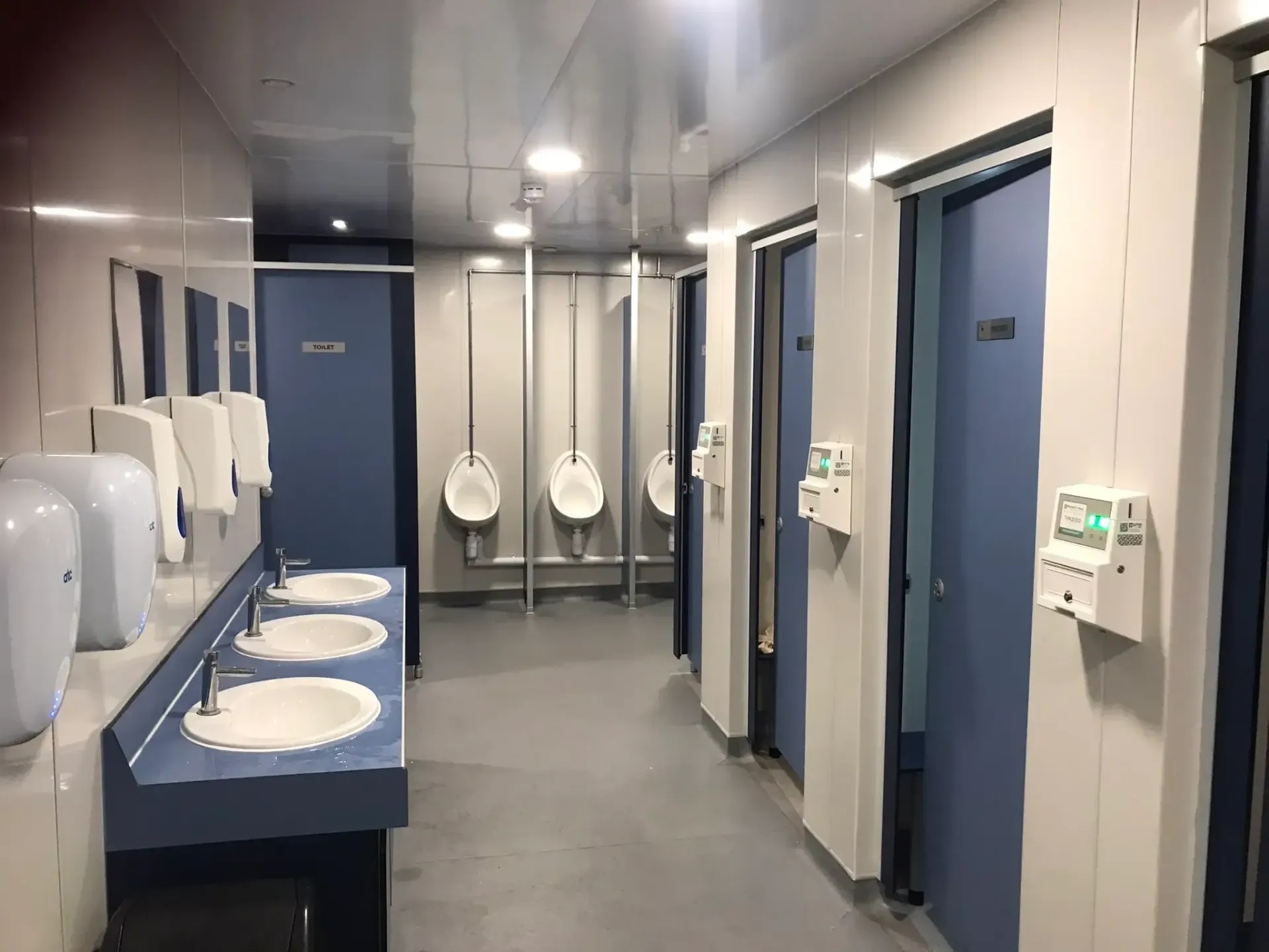 Driver bathroom with sinks, urinals, and stalls. White and blue colour scheme.