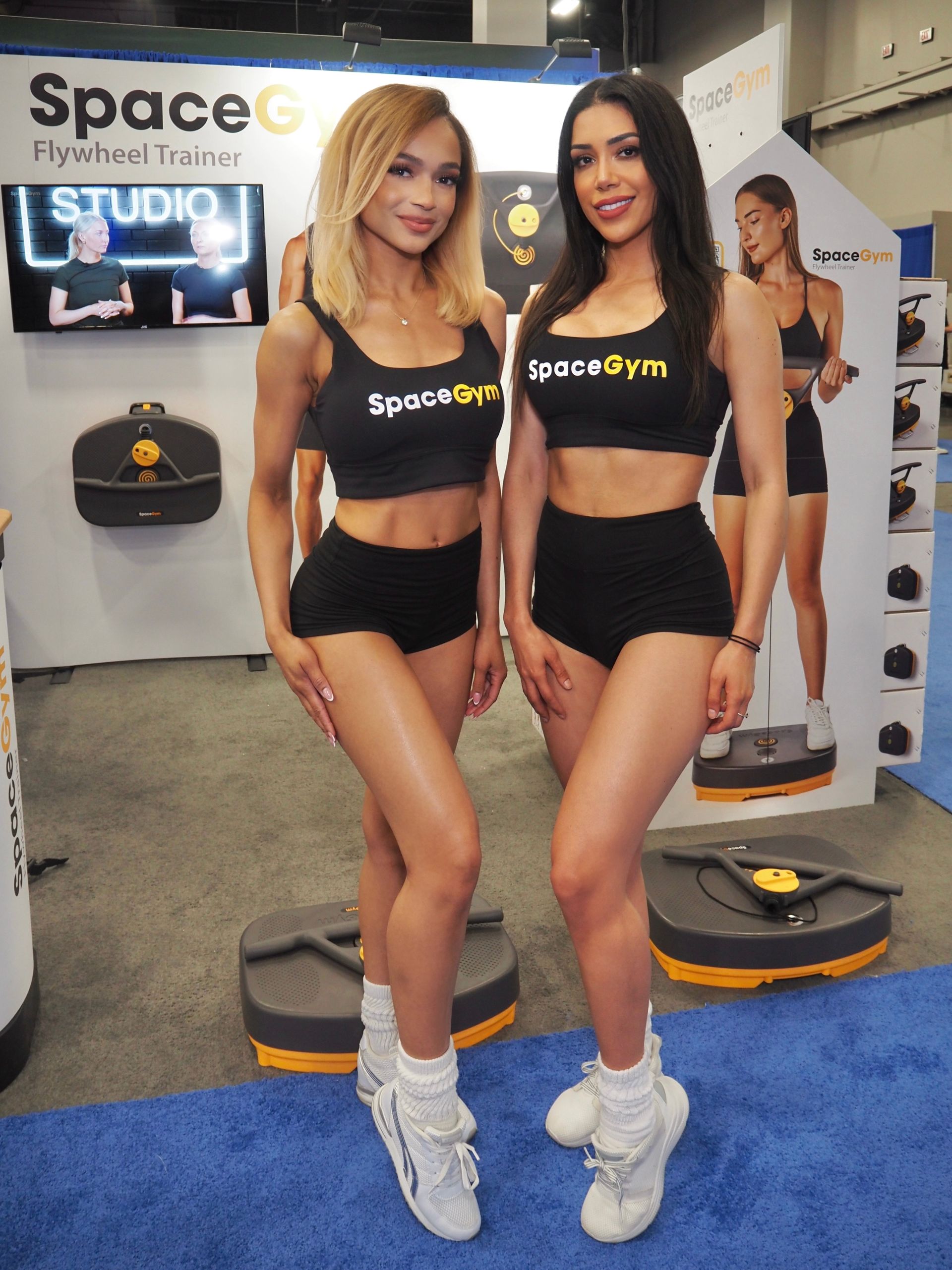 Fitness models pose for photos in Spacegym booth at HFA Las Vegas.